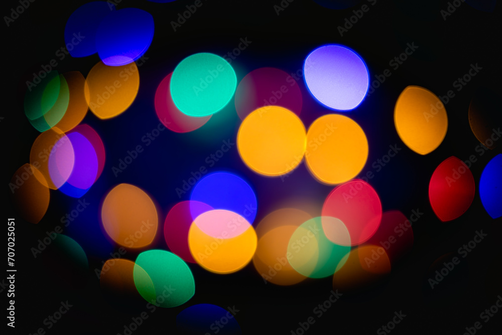 Colorful glowing lights in soft focus, blurred bokeh lights on black background, holiday bokeh festive Christmas elegant abstract background.