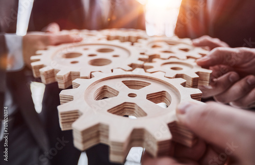 Business people holding wooden gears in office