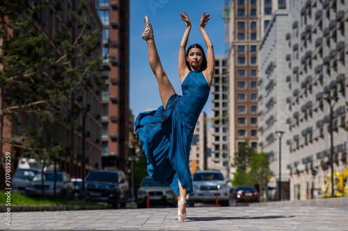 Beautiful Asian ballerina dancing outdoors. Urban landscape.