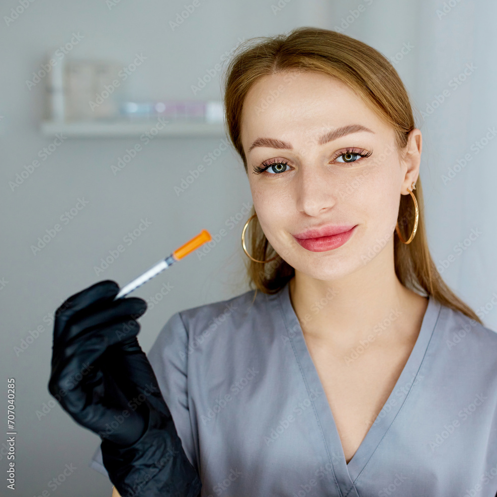 Obraz premium Portrait of a cosmetologist in the office with a syringe. Injection procedure for lip augmentation. Advertising concept for facial care, youth and beauty.