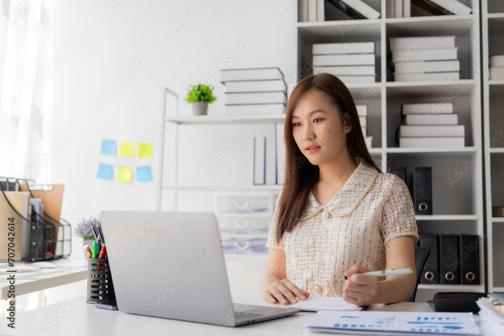 Working with finance and calculator in bank office, Asian female accountant working with laptop and financial documents in office Working with finance and calculator in bank office, Asian female accountant working with laptop and financial documents in office