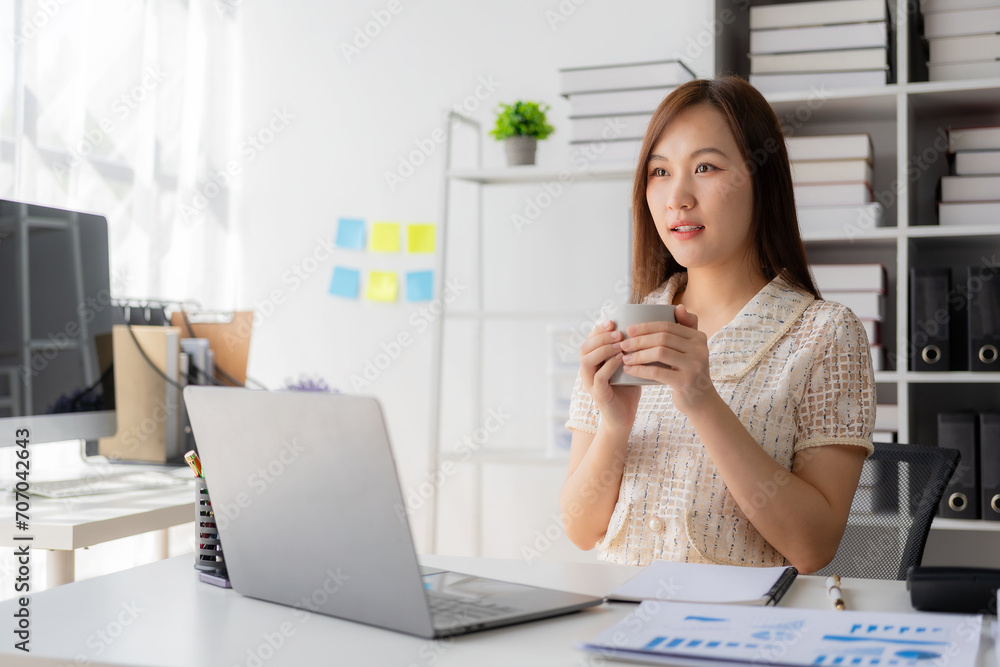 Working with finance and calculator in bank office, Asian female accountant working with laptop and financial documents in office Working with finance and calculator in bank office, Asian female accountant working with laptop and financial documents in office