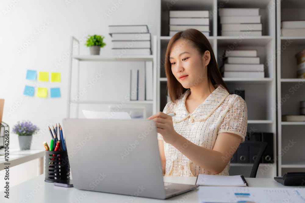 Working with finance and calculator in bank office, Asian female accountant working with laptop and financial documents in office Working with finance and calculator in bank office, Asian female accountant working with laptop and financial documents in office