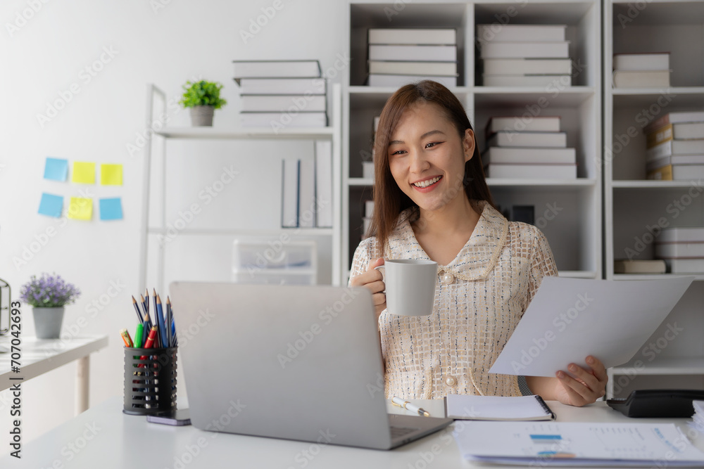 Working with finance and calculator in bank office, Asian female accountant working with laptop and financial documents in office Working with finance and calculator in bank office, Asian female accountant working with laptop and financial documents in office