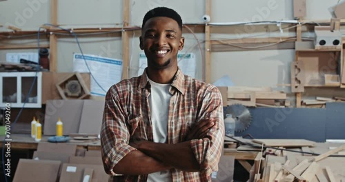 Jubilant African American males fixes shirt and poses for photograph in woodwork factory photo