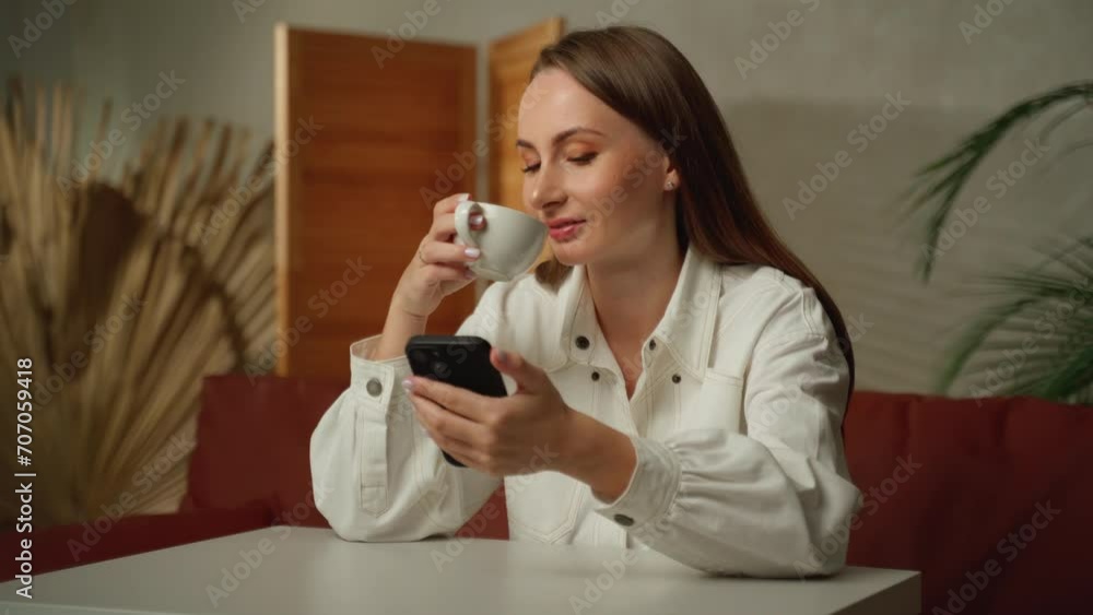 Woman looks at her phone while working in the office Woman looks at her phone while working in the office