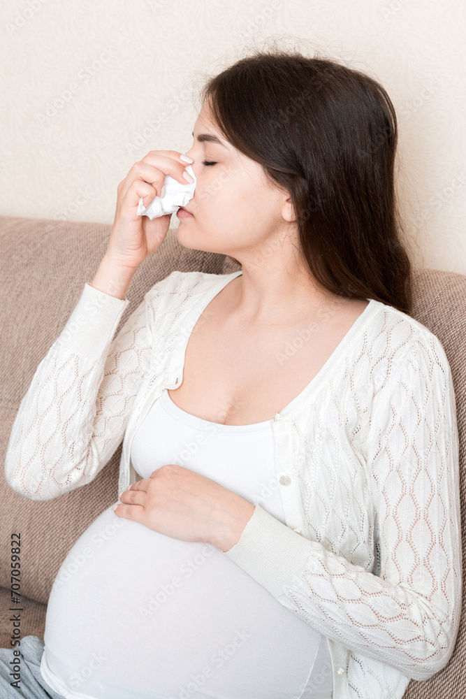 Sick pregnant woman blowing nose into tissue at home Healthy millennial healthcare concept Sick pregnant woman blowing nose into tissue at home Healthy millennial healthcare concept