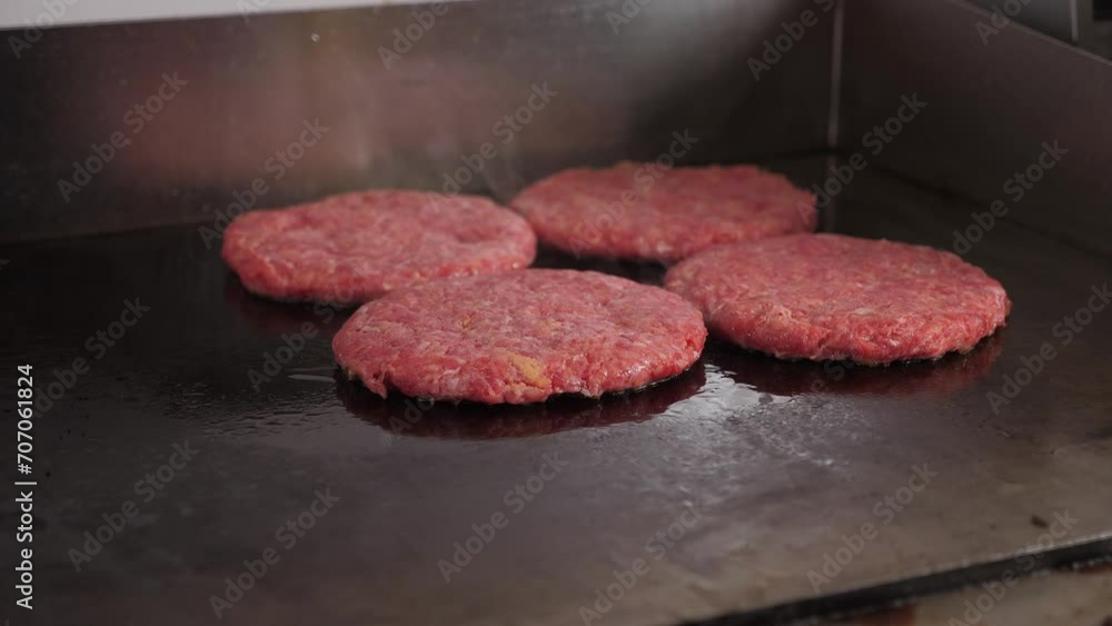 Close-up of four burger patties fried on a hot industrial stove in the restaurant kitchen. The process of cooking juicy mouth-watering burgers. Fast food. Close-up of four burger patties fried on a hot industrial stove in the restaurant kitchen. The process of cooking juicy mouth-watering burgers. Fast food.