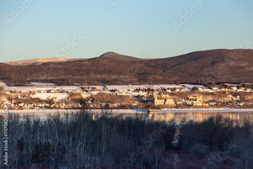  Row of trees seen in winter, with the St. Lawrence River and the Ste. Anne-de-Beaupre basilica at the foot of the Laurentian mountains in soft focus background, Sainte-Famille, Island of Orleans