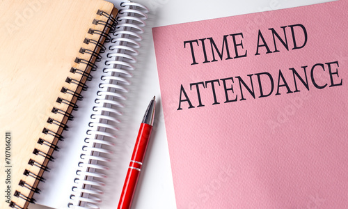 Foto TIME AND ATTENDANCE word on the pink paper with office tools on white background