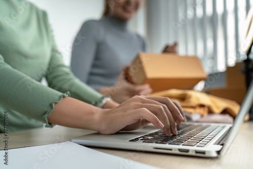 Young woman online business owner is typing details on a laptop in preparation for sending products to customers