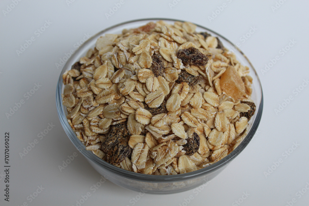Muesli is rolled oats mixed with nuts, seeds, and dried fruits. In a transparent bowl, isolated on white background Muesli is rolled oats mixed with nuts, seeds, and dried fruits. In a transparent bowl, isolated on white background