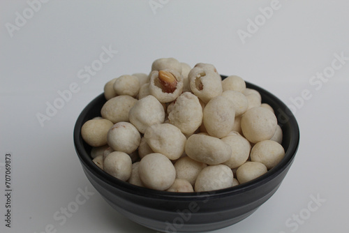 Kacang Atom  snack from Indonesia  made from peanut covered by flour dough then fried. On black bowl  isolated on white background