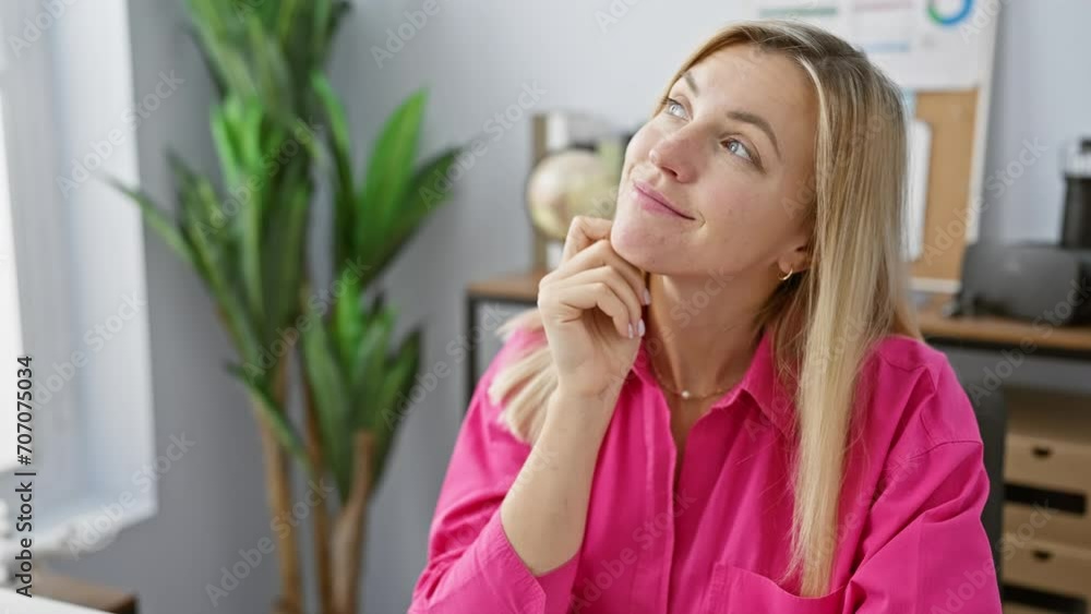 A thoughtful woman in pink shirt posing in a modern office with blurred background. A thoughtful woman in pink shirt posing in a modern office with blurred background.