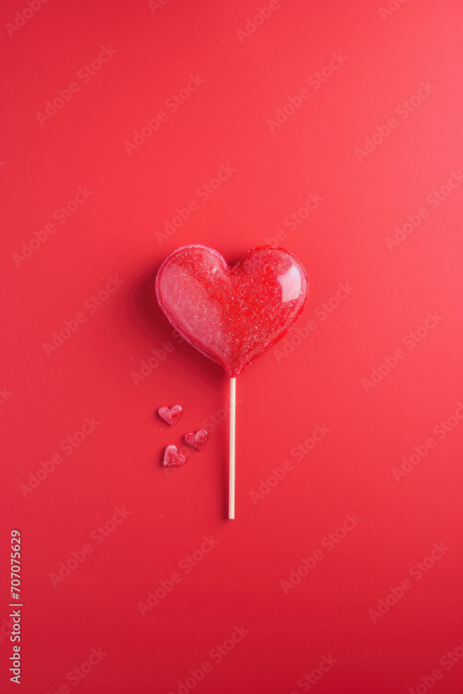 Red heart shaped lollipop on a red background, top view. Red heart shaped lollipop on a red background, top view.
