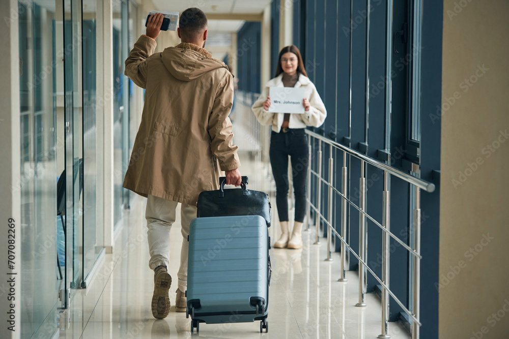 Greetings gesture, arrival of the man. Couple are in the airport hall together Greetings gesture, arrival of the man. Couple are in the airport hall together