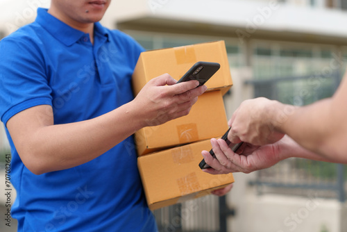 Delivery worker, SME entrepreneur, online sales concept, delivery, SME parcel box, procurement, delivery, customer holds the parcel box and scans to pay online application on mobile phone at home. photo