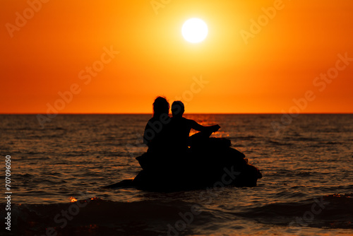 Man woman on a jet scooter on the sea at sunset