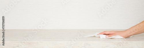 Cuadro en lienzo Young adult woman hand holding white dry paper napkin and wiping beige stone tabletop at home kitchen