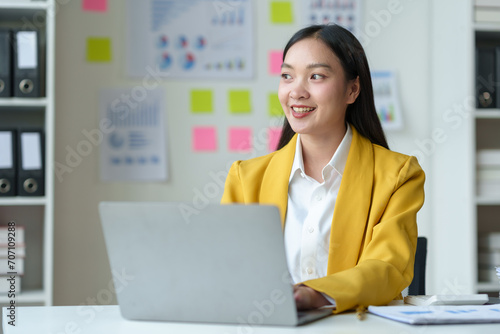 Cheerful businesswoman working with laptop in office, chatting Look at the laptop and talk about business, marketing, presentations video conference call meeting online training working in the office © crizzystudio
