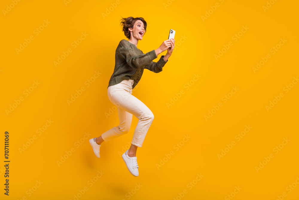 Photo of funky crazy cool girl wearing stylish clothes running empty space reading social media isolated on yellow color background