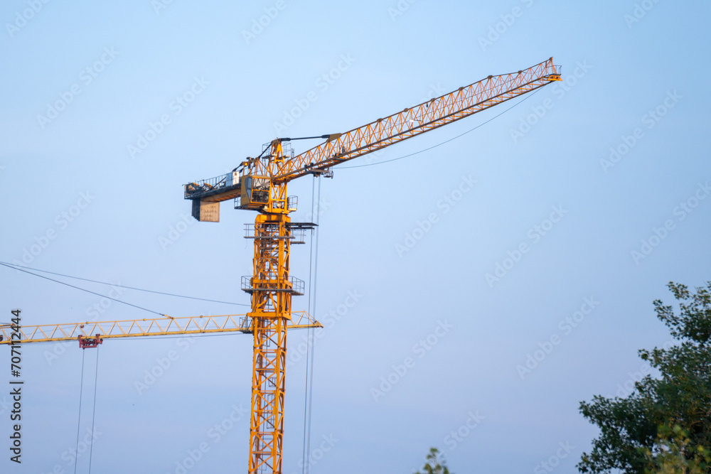 Construction crane stands tall and poised atop a power line in the midst of a bustling city. Construction crane stands tall and poised atop a power line in the midst of a bustling city.