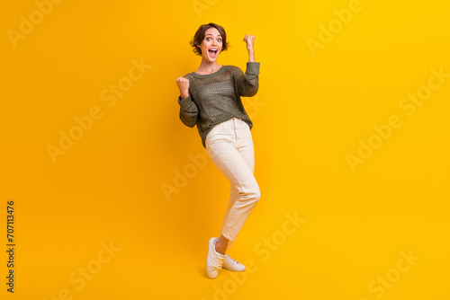 Photo of cheerful glad girl celebrating success achievement yelling yeah hooray isolated on yellow color background
