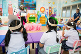 Rearview of elementary school children participating in a class activity with their teacher.