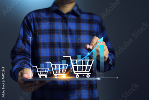 The growth of online shopping concept with a man holding tablet and shopping cart increase line chart graph head up to step by step photo