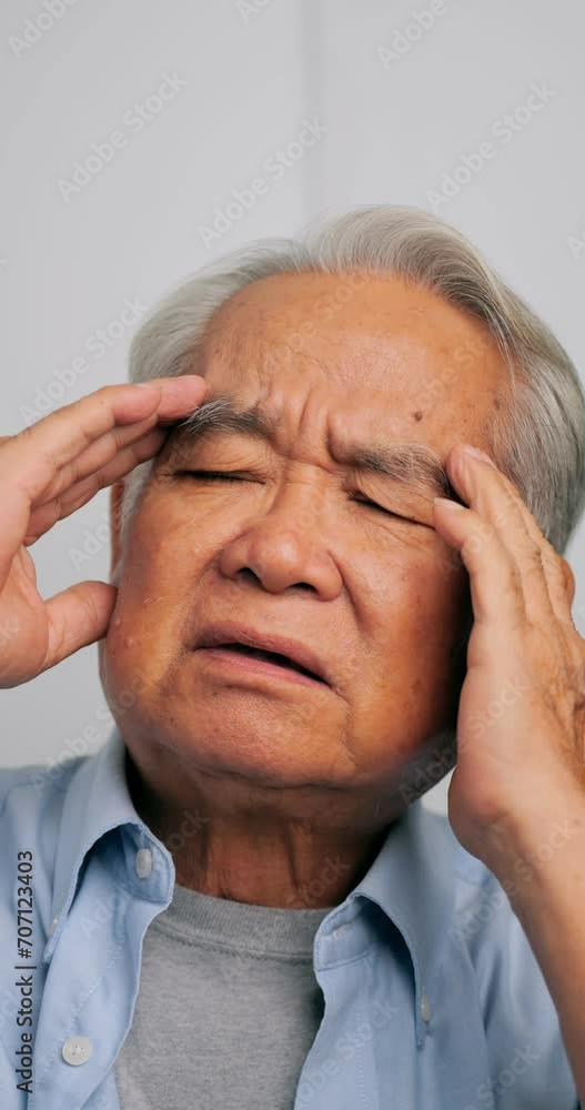 Vertical clip. Asian old man with migraine headache. Elderly man suffering from a headache.
