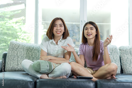 asian woman and friend sit at home on sofa bed watch tv movie.