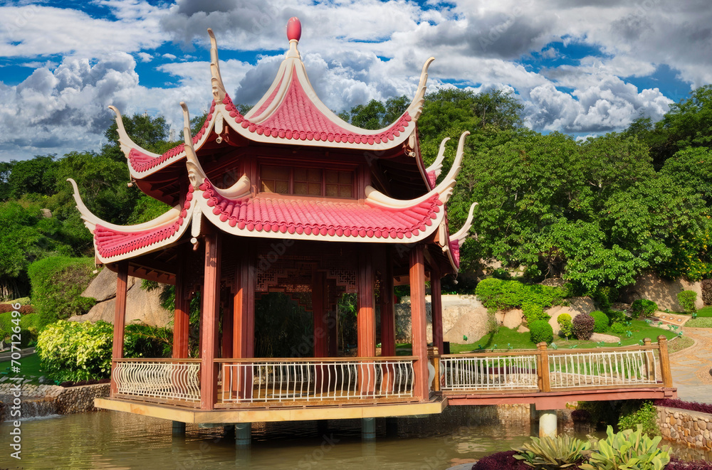 Traditional East Asian Pavilion with Curved Roof and Upturned Eaves Over Water, Surrounded by Lush Greenery