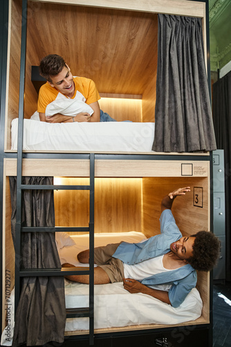 Canvas Print excited african american student lying on double-decker bed and waving hand to f
