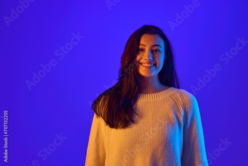 Eye Contact. Portrait of young girl looks directly at the camera, establishing strong connection with viewer against gradient blue background. Concept of positive emotions, fashion and beauty. Ad © Lustre Art Group 