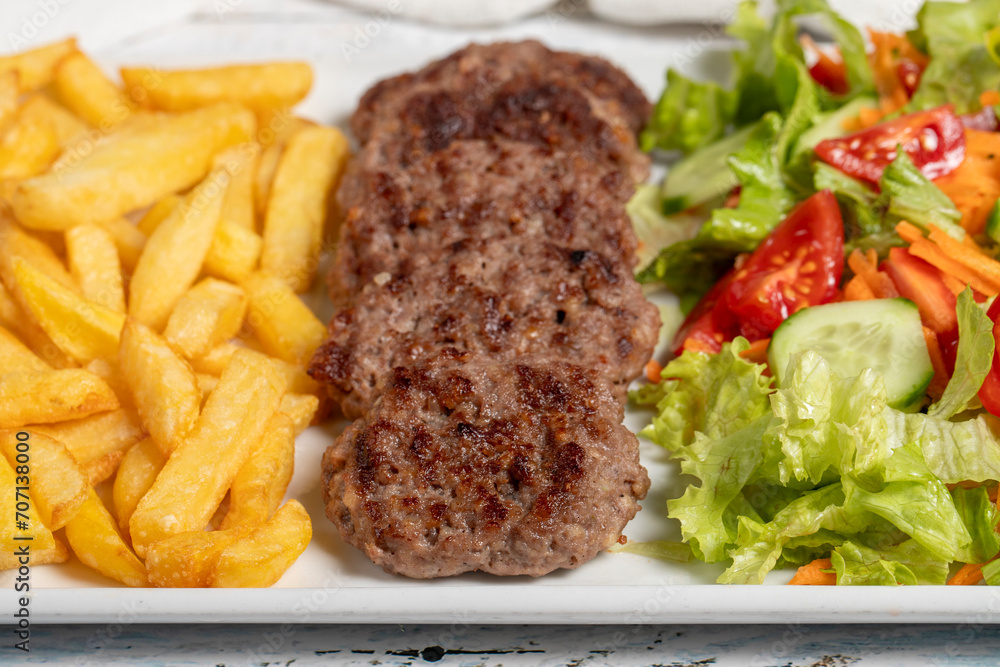 Grilled meat balls. Grilled meatballs with salad and fries on a white background. Close up