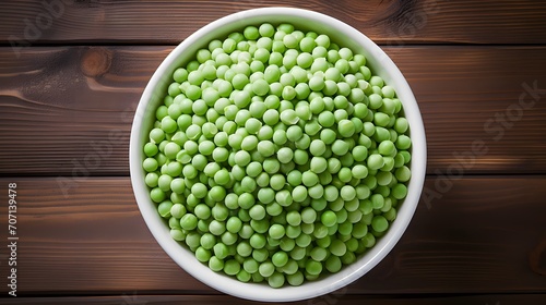Green peas in white bowl on wooden background, top view © Ziyan Yang