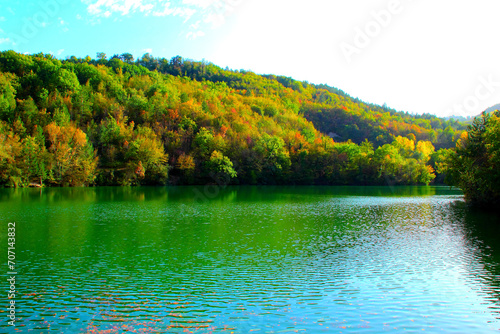 Energizing view at Lago di Boccafornace in Pievebovigliana, Valfornace (Macerata) with the linear rippling waters of the lake shining on its wide emerald surface, a charming visual amongst fall trees photo