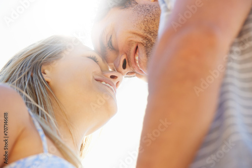 Forehead, eye contact or happy couple hug in outdoor on date for support or love in nature together. Low angle, romantic man or woman with smile on holiday vacation for fun bond, travel or wellness