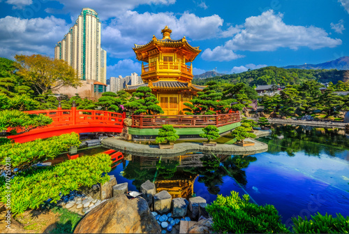 Serene Asian Garden Oasis with Golden Pavilion and Red Bridge Amidst Urban High-rises