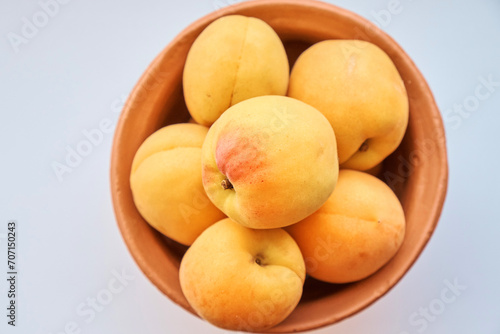 Apricots lie in a clay jug on a white background. View from above. Up close