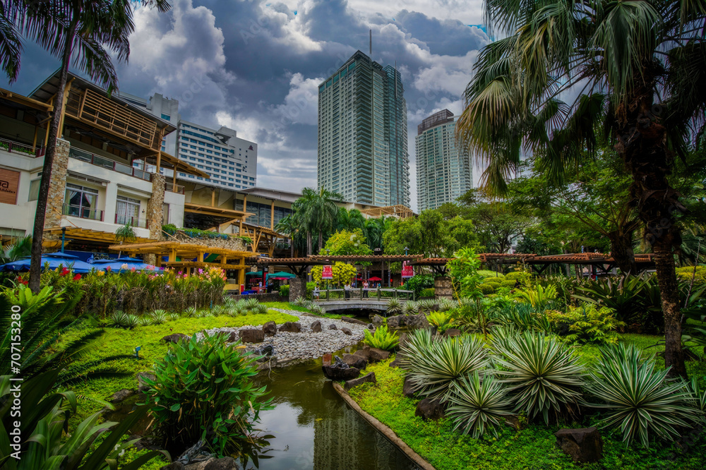 Lush Urban Oasis with Tropical Plants and Stream Amidst High-Rise Buildings in a Modern City