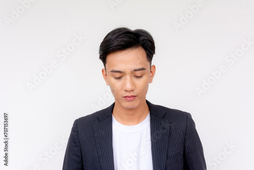 A young asian man looking disappointed in himself. Headshot isolated in a white background. photo