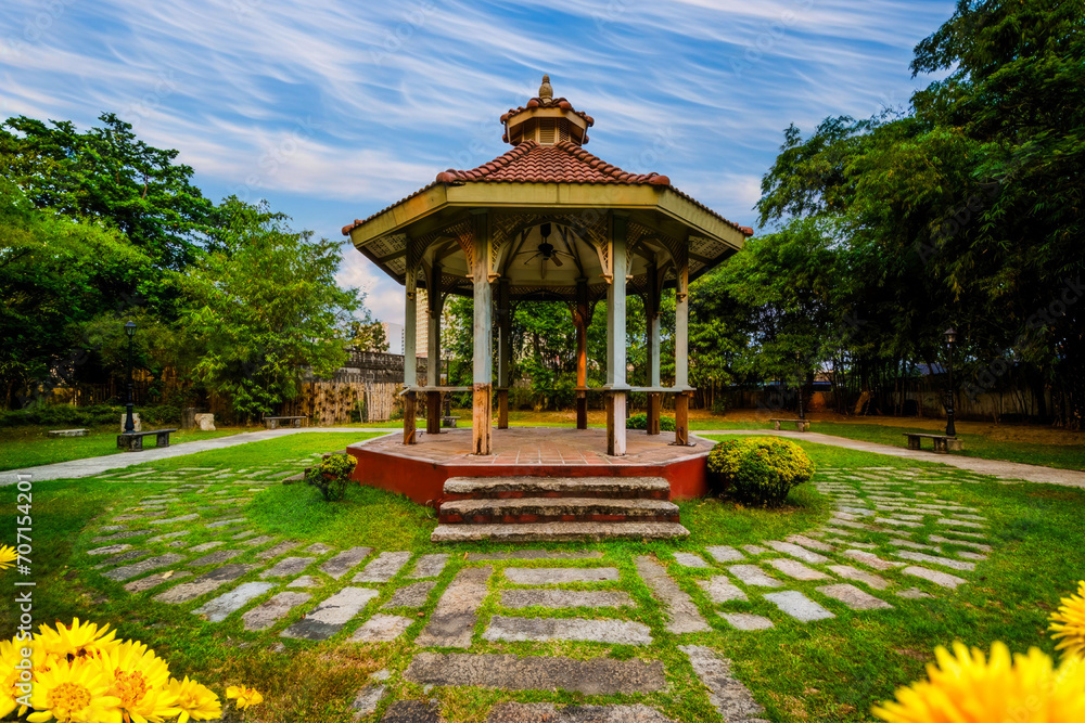 Traditional Gazebo in Serene Park with Lush Green Lawn, Vibrant Flowers, and Stone Pathway