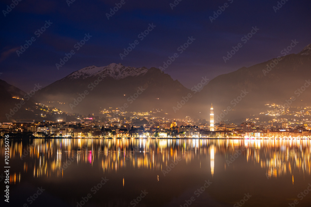 The city of Lecco, with its lakeside promenade and its buildings, photographed in the evening in winter.