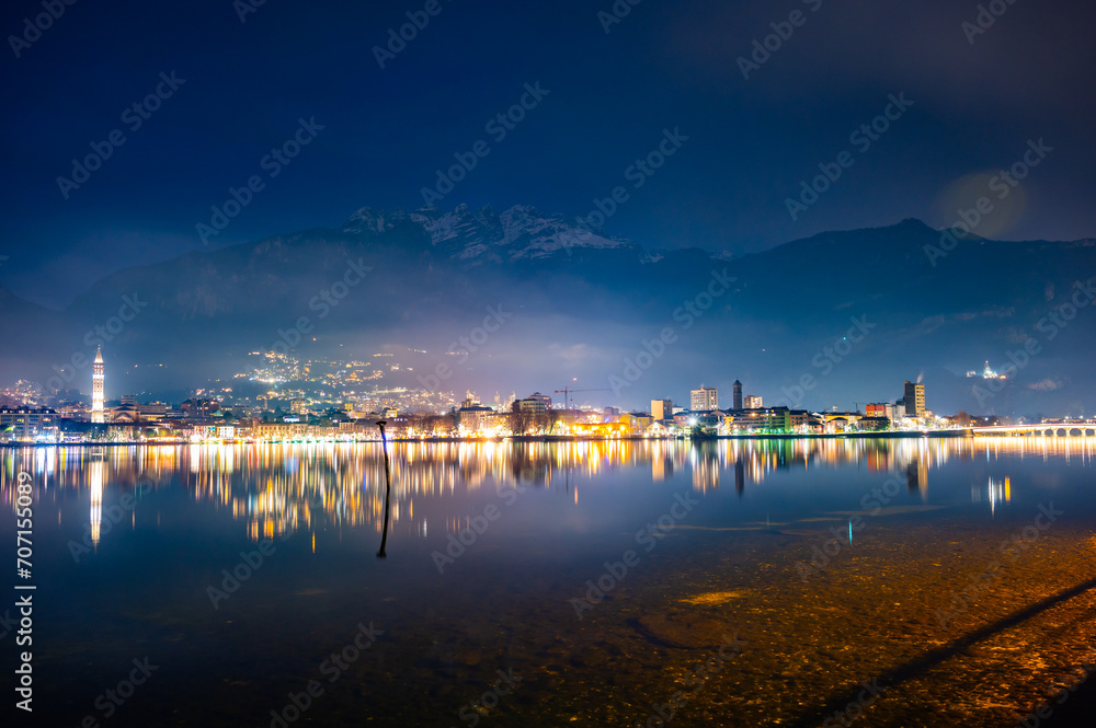 Naklejka premium The city of Lecco, with its lakeside promenade and its buildings, photographed in the evening in winter.