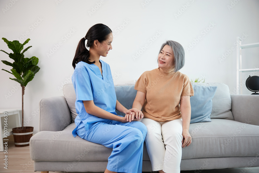 caregiver or nursing home holding hands and talking with senior woman on sofa caregiver or nursing home holding hands and talking with senior woman on sofa