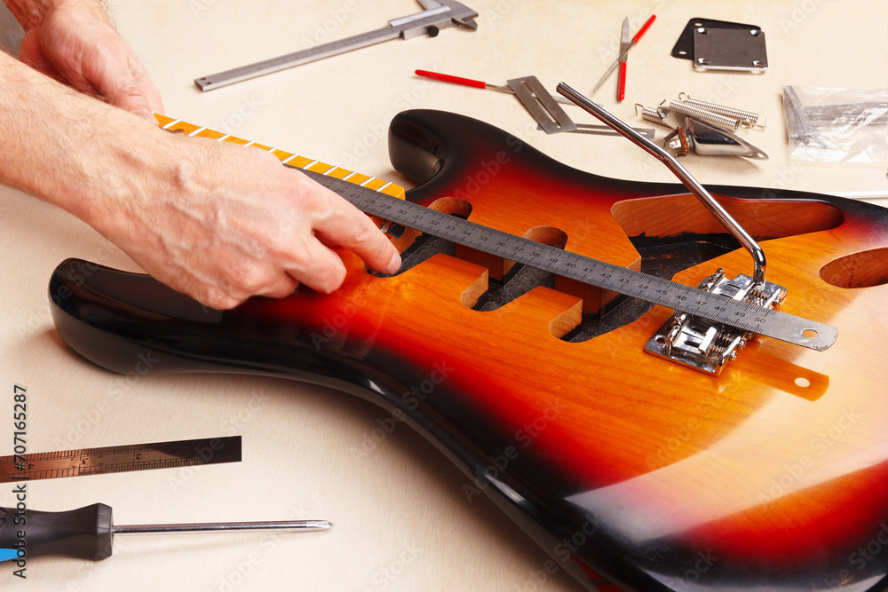 Guitar master measures distance of tremolo installation on electric
