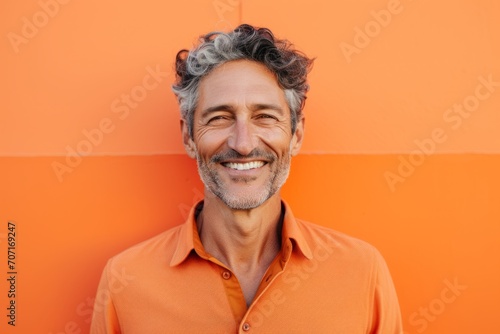 Portrait of a handsome middle-aged man smiling against orange wall © Igor