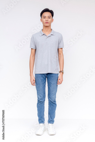 A slim young asian man wearing a gray shirt and jeans. Front view, whole body shot, isolated on a white background.