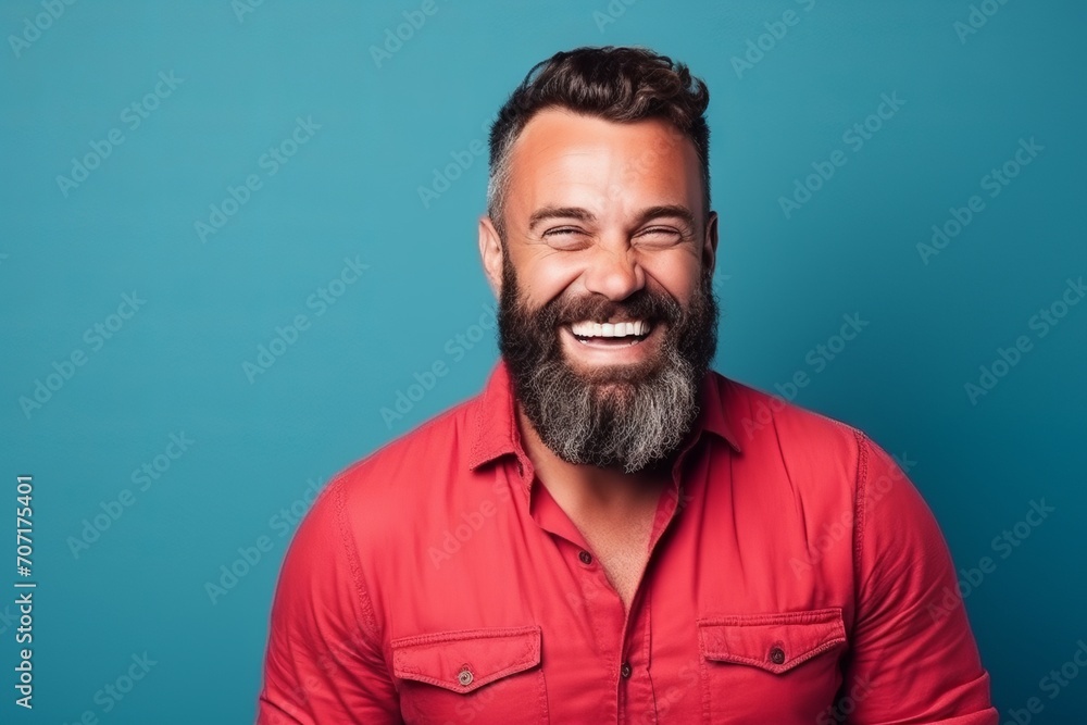 Portrait of a handsome man with beard and mustache laughing over blue background Portrait of a handsome man with beard and mustache laughing over blue background